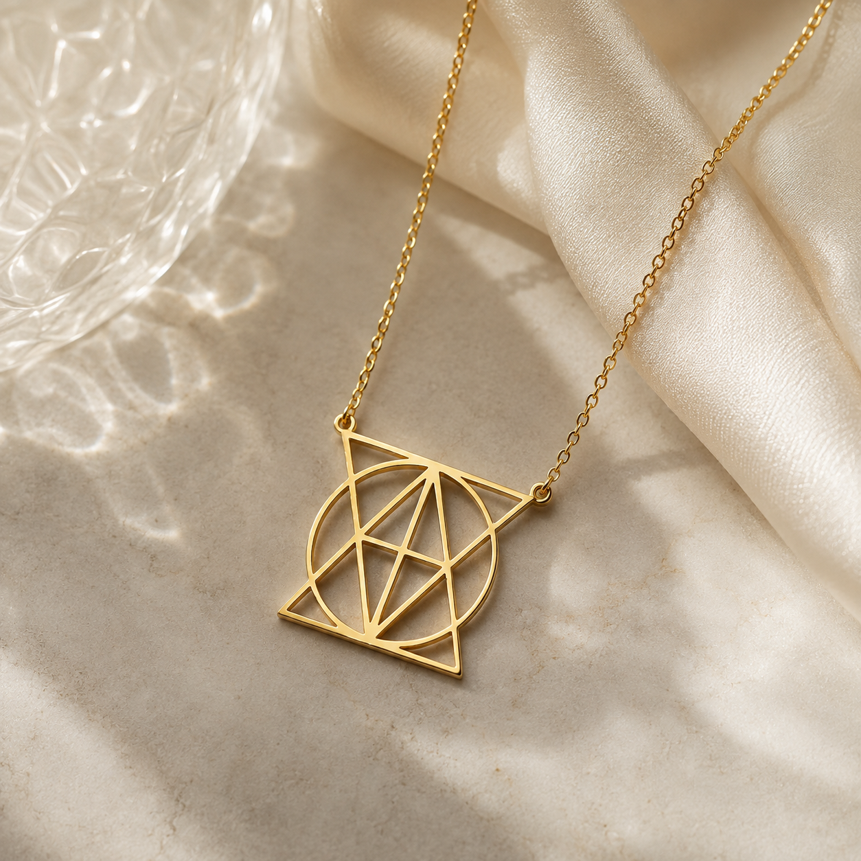 18K gold-plated geometric name necklace displayed on cream satin